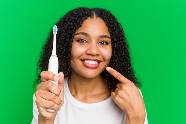 Joven afroamericano usando un cepillado de dientes aislado