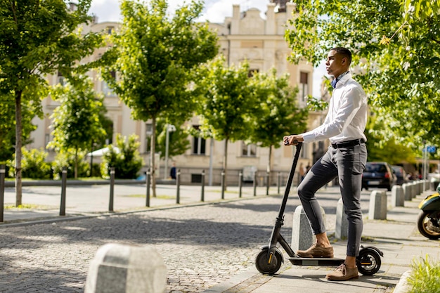 Joven afroamericano usando scooter eléctrico en una calle