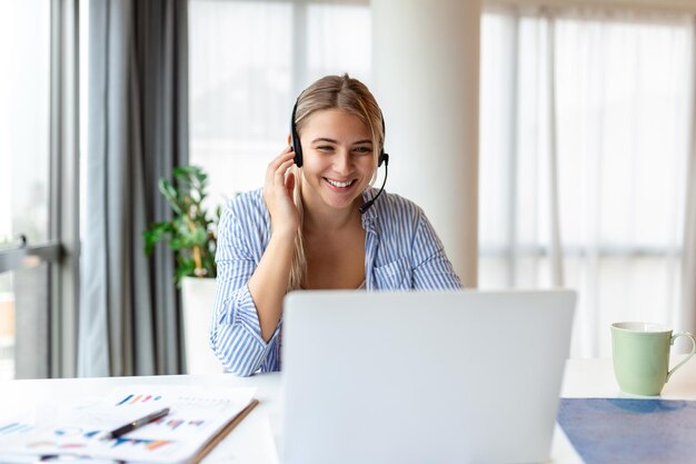 Joven agente de operador mujer amigable con auriculares hermosa mujer de negocios que usa auriculares de micrófono trabajando en la oficina como agente de servicio al cliente de telemarketing concepto de trabajo de centro de llamadas
