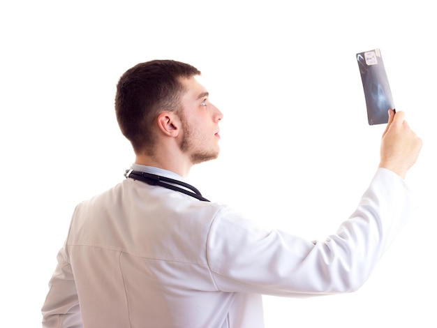 Un joven agradable con camisa azul, corbata y bata de médico con estetoscopio en el cuello sosteniendo Xray