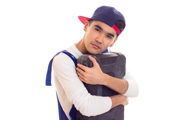 Un joven agradable con camisa blanca y azul en general con guantes naranjas y una caja de herramientas con gorra azul