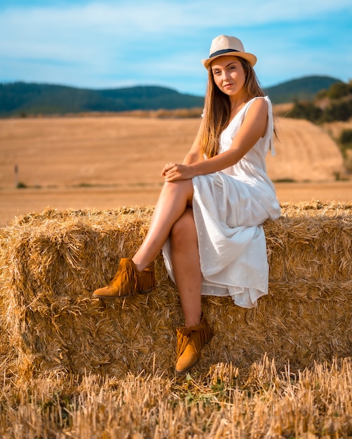 Joven agricultor caucásico rubio con vestido blanco y sombrero blanco en verano
