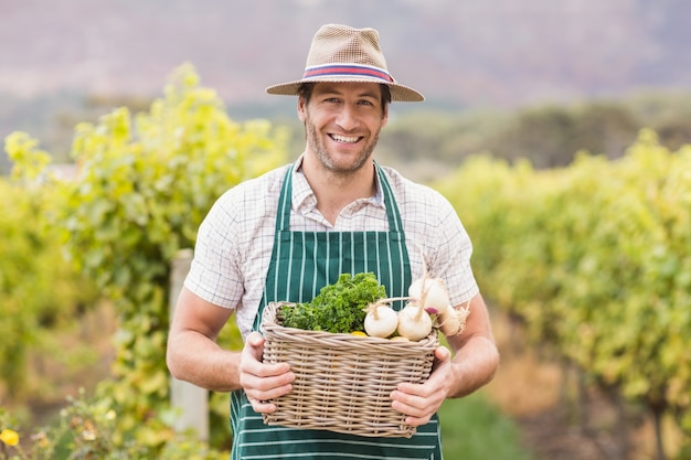 Joven agricultor feliz sosteniendo una cesta de verduras