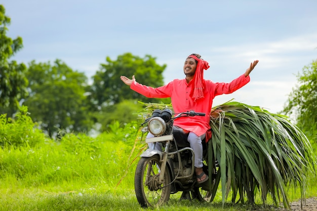 Joven agricultor indio con comida para el ganado en una moto