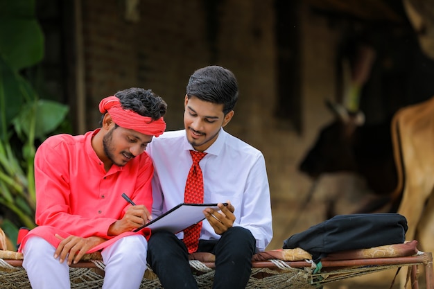 Joven agricultor indio firmando un documento con el banquero en casa