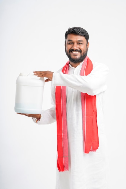 Joven agricultor indio mostrando botella de fertilizante sobre fondo blanco.