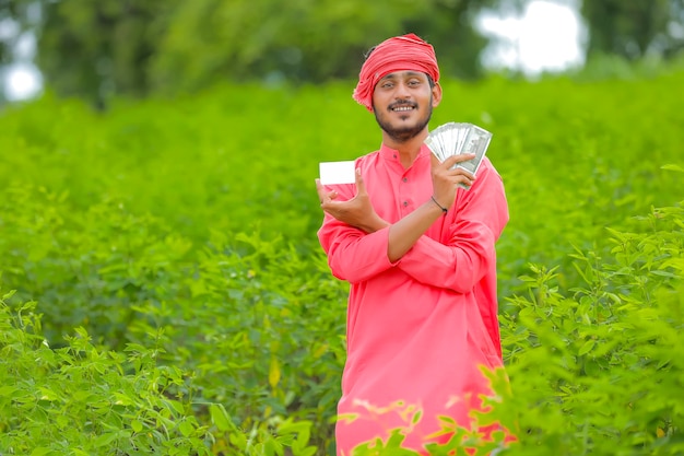 Joven agricultor indio mostrando dinero y una tarjeta