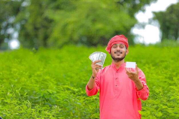 Joven agricultor indio mostrando dinero y una tarjeta