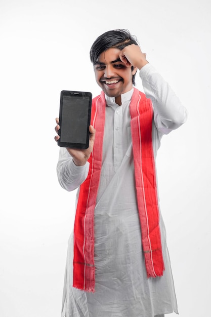 Joven agricultor indio mostrando teléfono inteligente o tableta y dando expresión sobre fondo blanco