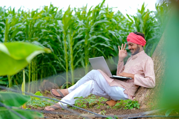 Joven agricultor indio con portátil en el campo de la agricultura.