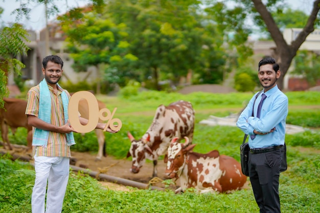 Joven agricultor indio que muestra el símbolo del cero por ciento con el ingeniero agrónomo o financiero en su finca ganadera