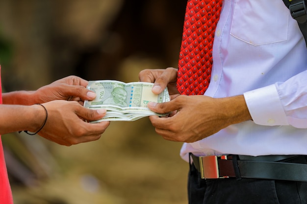 Joven agricultor indio recibiendo dinero de un banquero