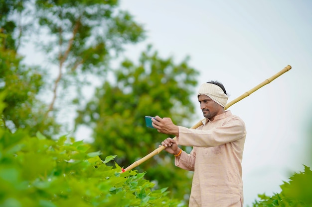 Joven agricultor indio con smartphone en el campo de la agricultura.