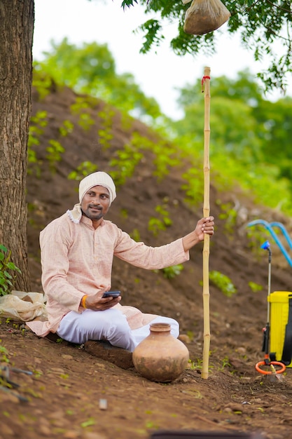 Joven agricultor indio con smartphone en el campo de la agricultura.