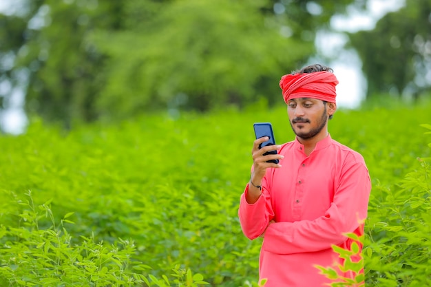 Joven agricultor indio con smartphone en un campo verde