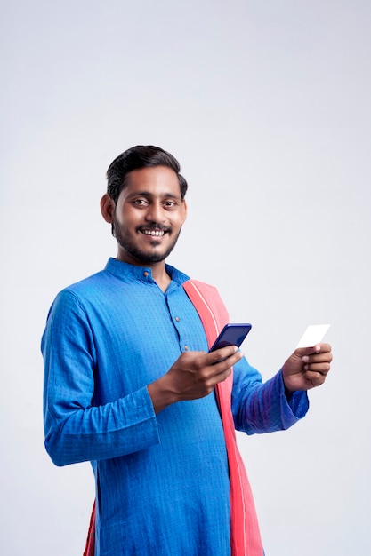 Joven agricultor indio con smartphone y tarjeta bancaria sobre fondo blanco.