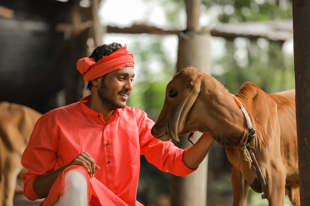 Joven agricultor indio con su vaca en la granja