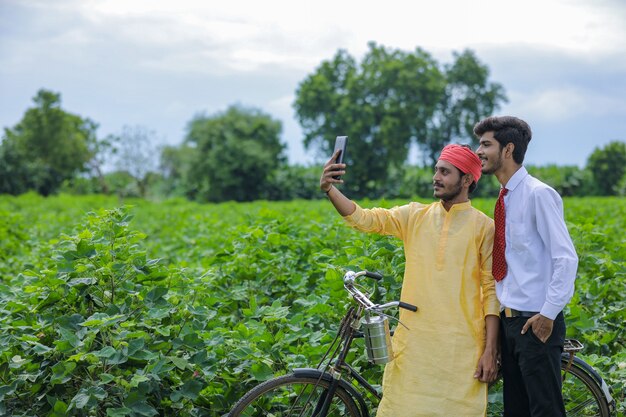 Joven agricultor indio tomar selfie con agrónomo en smartphone