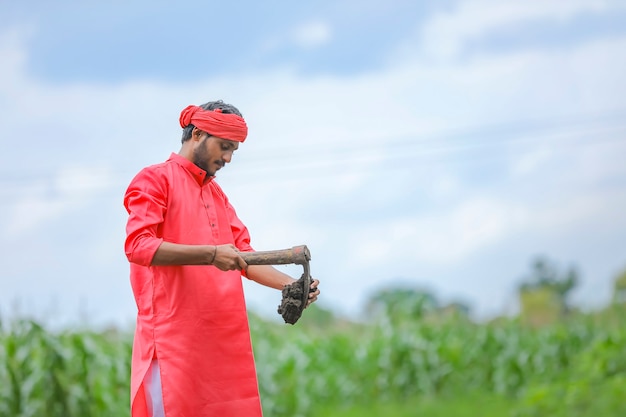 Joven agricultor indio trabajando duro con maquinaria agrícola en su campo