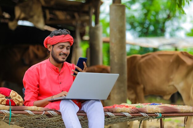 Joven agricultor indio usando una computadora portátil