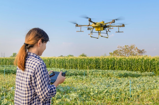 Un joven agricultor inteligente que controla la fumigación con drones de fertilizantes y pesticidas sobre las tierras de cultivoInnovaciones de alta tecnología y agricultura inteligente