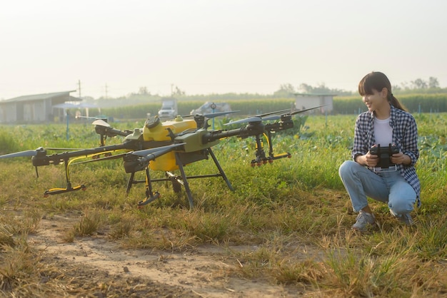 Un joven agricultor inteligente que controla la fumigación de fertilizantes y pesticidas con drones sobre las tierras de cultivo