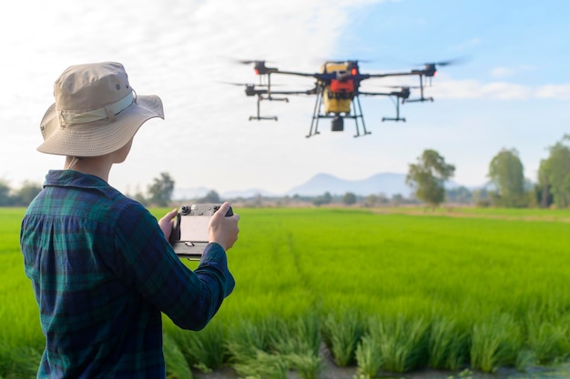 Un joven agricultor inteligente que controla la fumigación de fertilizantes y pesticidas con drones sobre las tierras de cultivo
