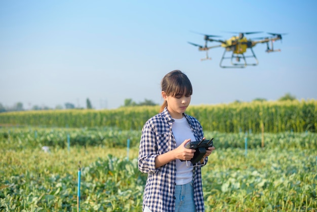 Un joven agricultor inteligente que controla la fumigación de fertilizantes y pesticidas con drones sobre las tierras de cultivo