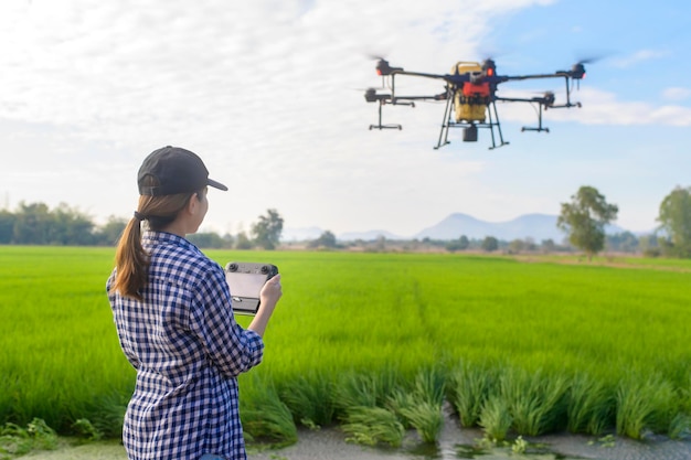 Un joven agricultor inteligente que controla la fumigación de fertilizantes y pesticidas con drones sobre las tierras de cultivo