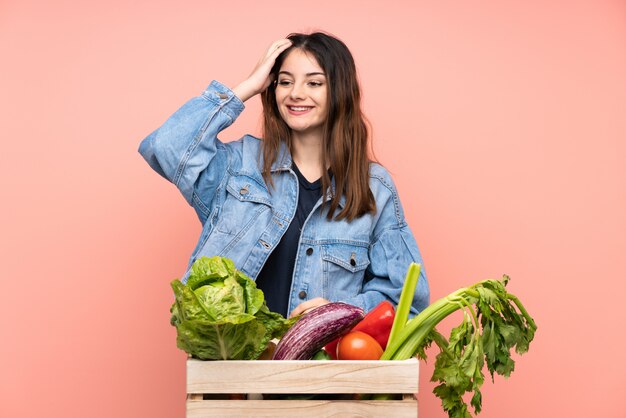 Joven agricultor mujer sosteniendo una canasta llena de verduras frescas riendo