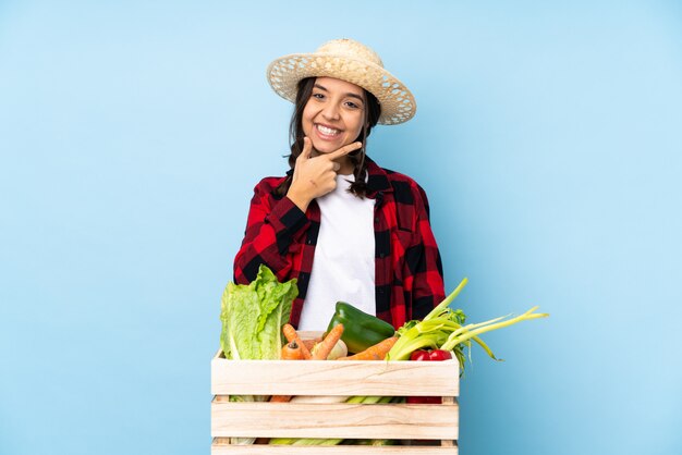 Joven agricultor Mujer sosteniendo verduras frescas en una cesta de madera sonriendo