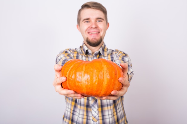 Joven agricultor sosteniendo una calabaza sobre un fondo claro studio