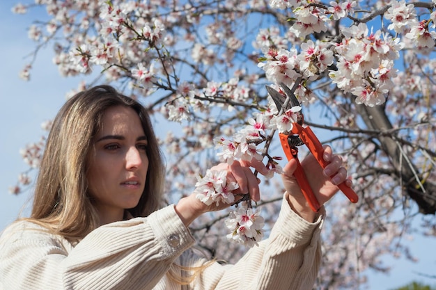 Joven agricultora cortando ramas de flores del árbol