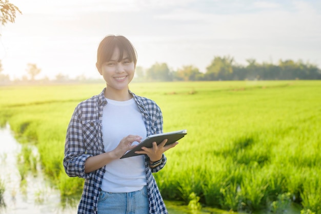 Una joven agricultora inteligente con tableta en el campo, innovaciones de alta tecnología y agricultura inteligente