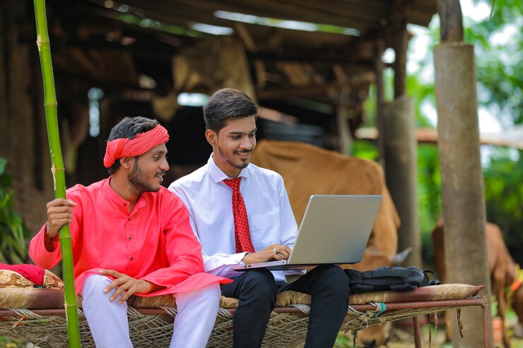 Foto joven agrónomo indio mostrando alguna información al agricultor en la computadora portátil en casa