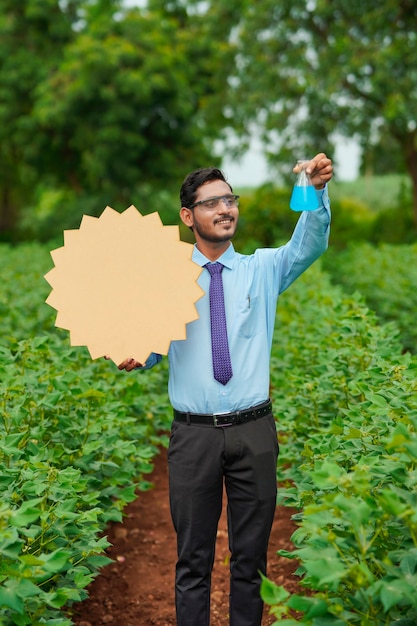 Joven agrónomo indio mostrando tablero con espacio de copia en el campo de la agricultura.