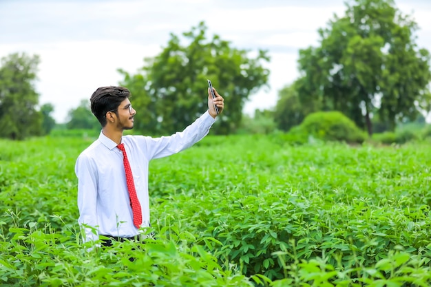 Joven agrónomo indio con smartphone en campo