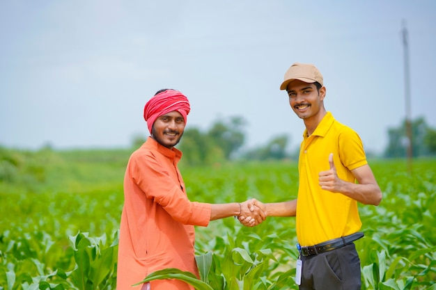 Joven agrónomo o banquero indio se dan la mano con el agricultor en el campo de la agricultura.