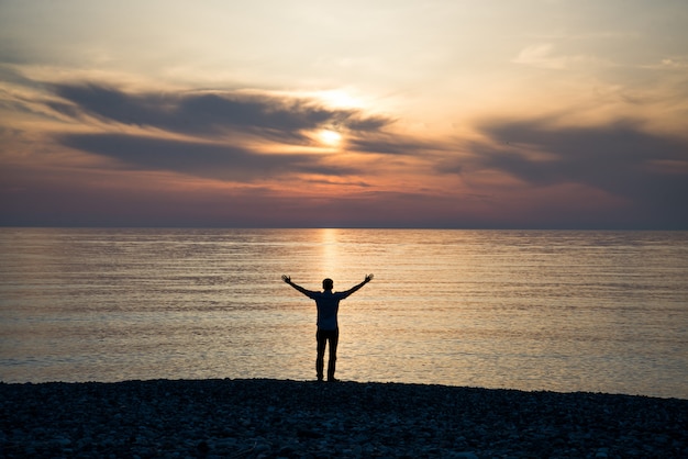 Joven al atardecer levanta sus manos