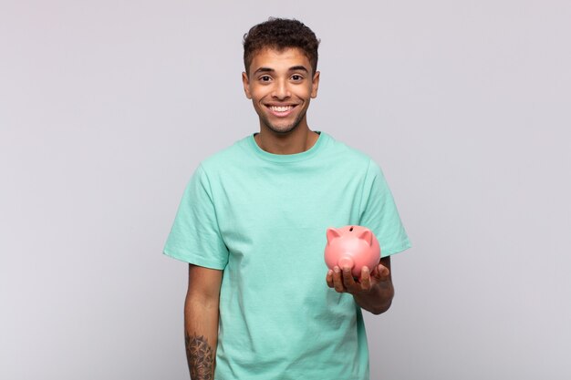 Joven con una alcancía que parece feliz y gratamente sorprendido, emocionado con una expresión fascinada y conmocionada