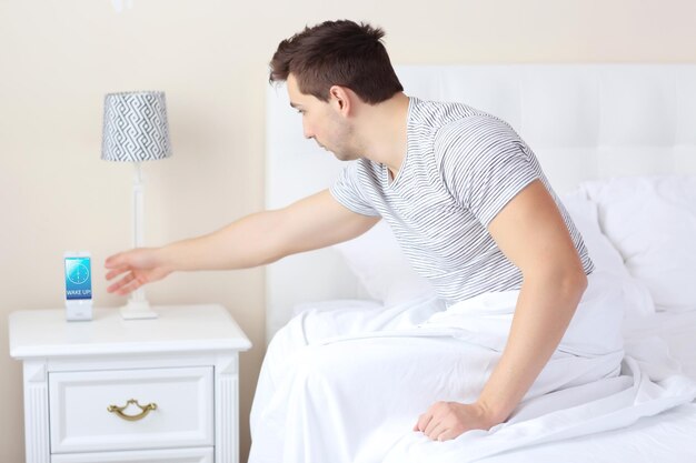 Joven alcanzando su teléfono Concepto para dormir