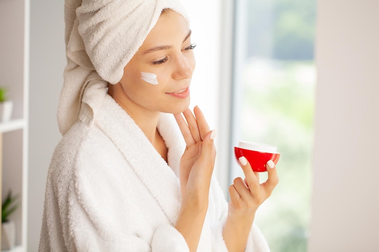Foto joven alegre aplicando crema hidratante en la cara