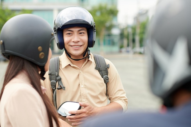 Joven alegre con casco protector cuando habla con amigos