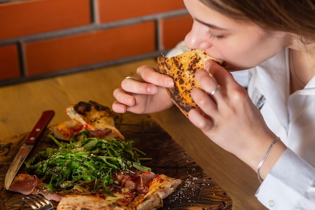 Una joven alegre disfrutando de una rebanada de pizza