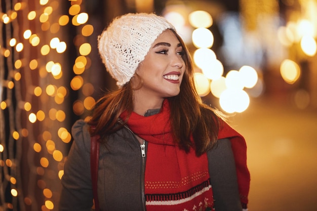 Una joven alegre se divierte y camina por las calles de la ciudad en Navidad.