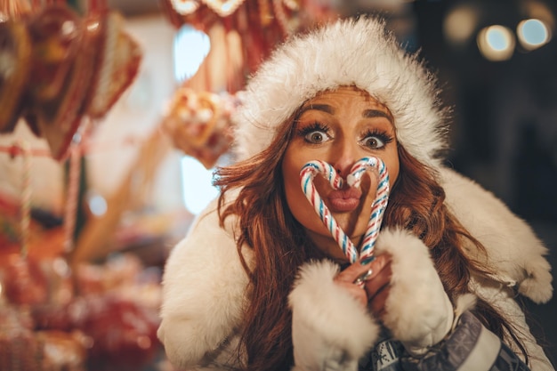 Una joven alegre se divierte en un mercado navideño en la calle de la ciudad en la noche de Año Nuevo.