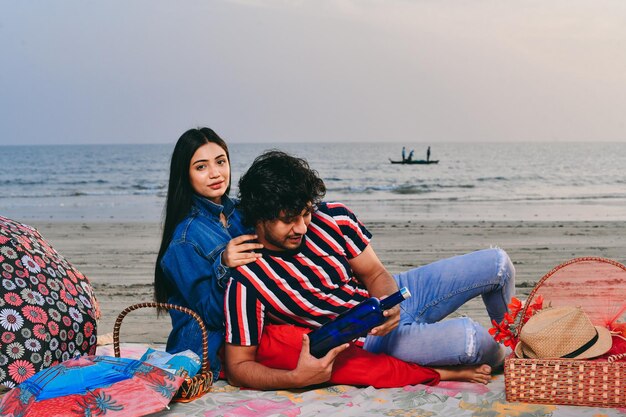 joven alegre feliz pareja sentada en la playa modelo pakistaní indio