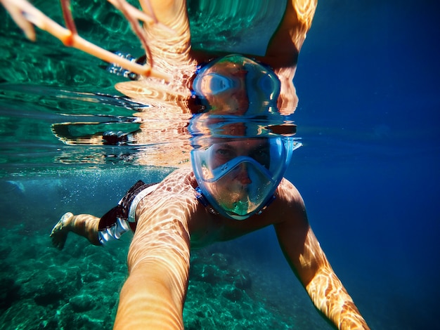 Joven alegre haciendo selfie en mar exótico.