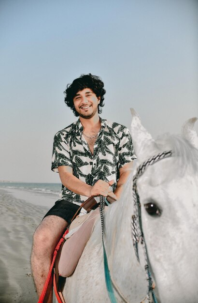 Joven alegre hombre feliz cabalgando en la playa modelo pakistaní indio