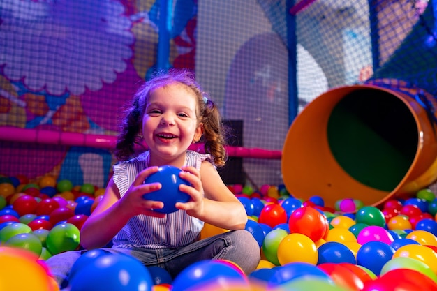 Una joven alegre jugando en un colorido pozo de pelota en un patio de recreo cubierto